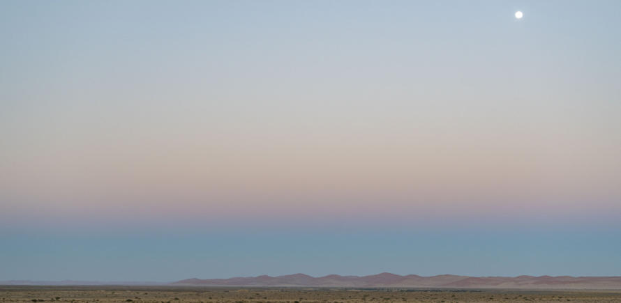 Blick auf die Namib bei Sonnenaufgang mit Vollmond am Himmel