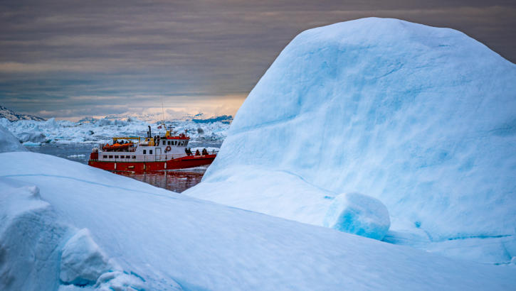 Wunderbarer Kontrast - rotes Fischerboot verschwindet hinter Eisberg