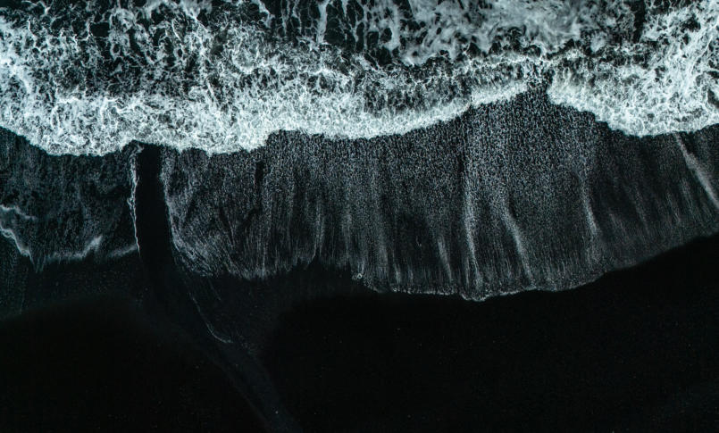 weiße Wellen auf schwarzem Strand