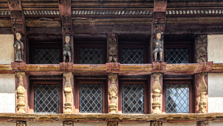 Geschnitze Holzfiguren umrahmen mittelalterliches Fenster in Vitré
